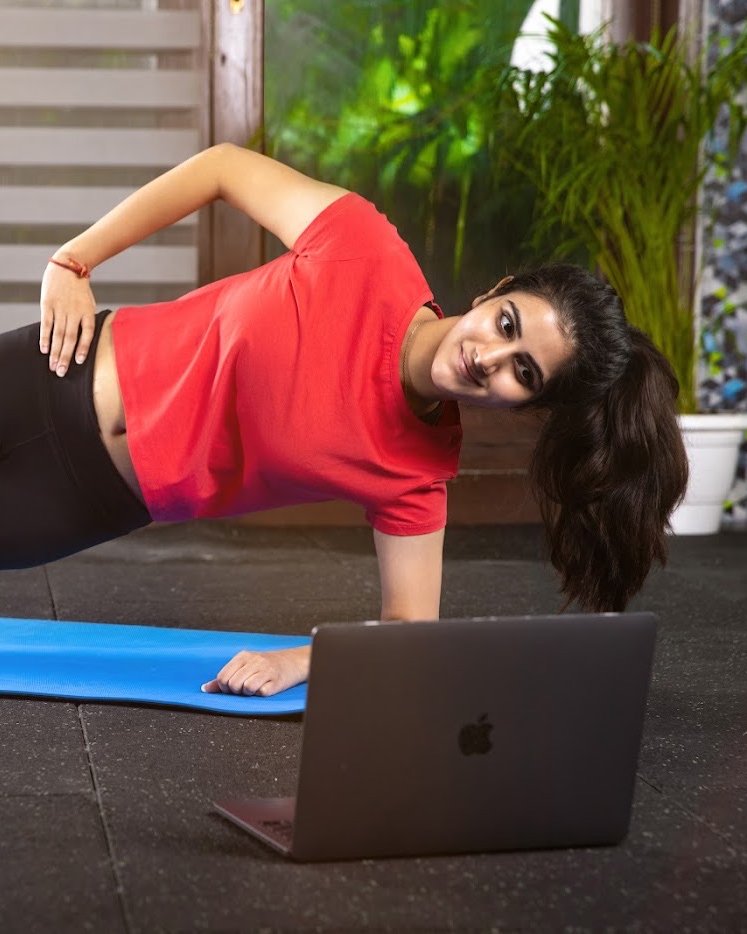 Woman doing a side plank at home while training live with her BoxFit coach on a laptop